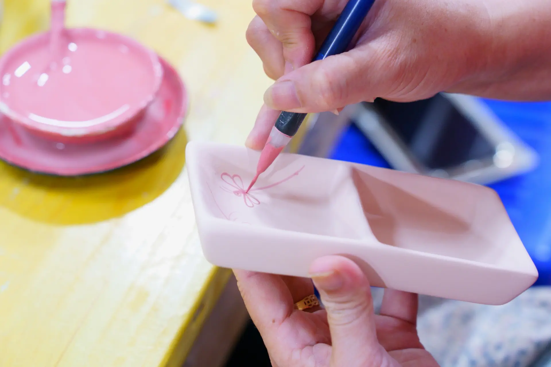 絵付けの様子。素焼きしたものに、下書きはせずに手作業でトンボや蓮を描いていく。